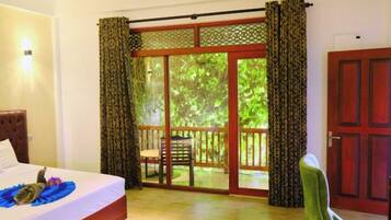 Quarto com cama, porta de vidro deslizante para uma varanda e porta de madeira.