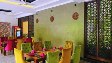 Un restaurante con varias mesas y sillas, un ventilador de techo y paneles decorativos en la pared.