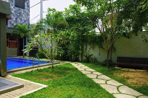 A residential backyard with a swimming pool, a stone pathway, and a bench. - Polhena Grand Resort & Banquet (Matara)