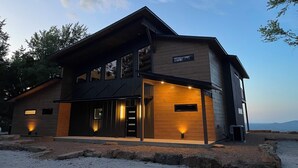 A modern two-story building with a prominent entrance, large windows, and a wooden facade.