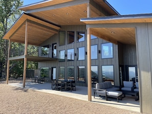Een modern herenhuis met twee verdiepingen en een overdekte patio met tuinmeubilair.