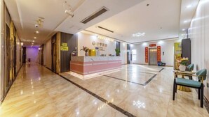 A hotel lobby with a reception desk, a waiting area with chairs, and a clean, polished floor. - Junyu Hotel (Guangdong Women's Vocational and Technical College Asian Games Village Branch) (Guangzhou)
