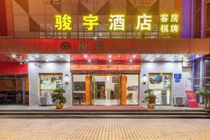 A hotel entrance with a prominent sign, a reception desk, and a potted plant outside. - Junyu Hotel (Guangdong Women's Vocational and Technical College Asian Games Village Branch) (Guangzhou)