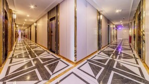 A hotel corridor with a geometric patterned floor, mirrored walls, and a modern design. - Junyu Hotel (Guangdong Women's Vocational and Technical College Asian Games Village Branch) (Guangzhou)