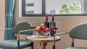 A table with a bowl of fruit, two wine bottles, and two glasses. - Junyu Hotel (Guangdong Women's Vocational and Technical College Asian Games Village Branch) (Guangzhou)