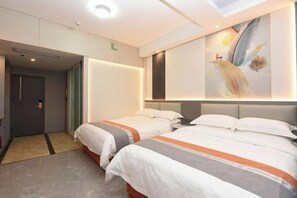 A hotel room with two beds, a large painting on the wall, and a door leading to another room. - Junyu Hotel (Guangdong Women's Vocational and Technical College Asian Games Village Branch) (Guangzhou)