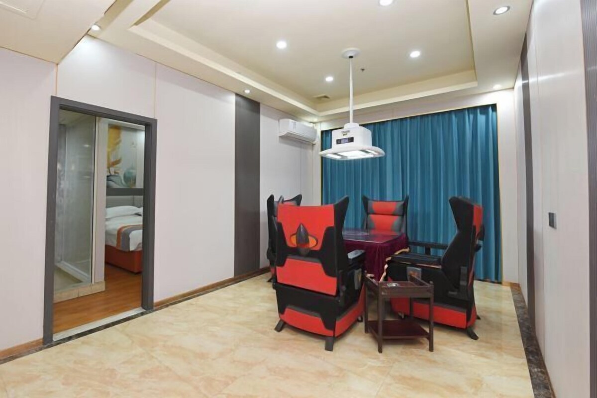 A hotel room with a bed, a desk, and a chair. There is a window with blue curtains and a ceiling light.