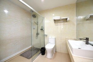 A modern bathroom with a glass-enclosed shower, a white toilet, a large bathtub, and a mirror. - Junyu Hotel (Guangdong Women's Vocational and Technical College Asian Games Village Branch) (Guangzhou)
