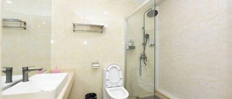 Un baño moderno con ducha acristalada, inodoro blanco y lavabo grande.