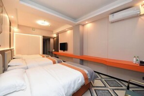 A hotel room with two beds, a flat-screen TV, an air conditioning unit, and a small table with bottles. - Junyu Hotel (Guangdong Women's Vocational and Technical College Asian Games Village Branch) (Guangzhou)