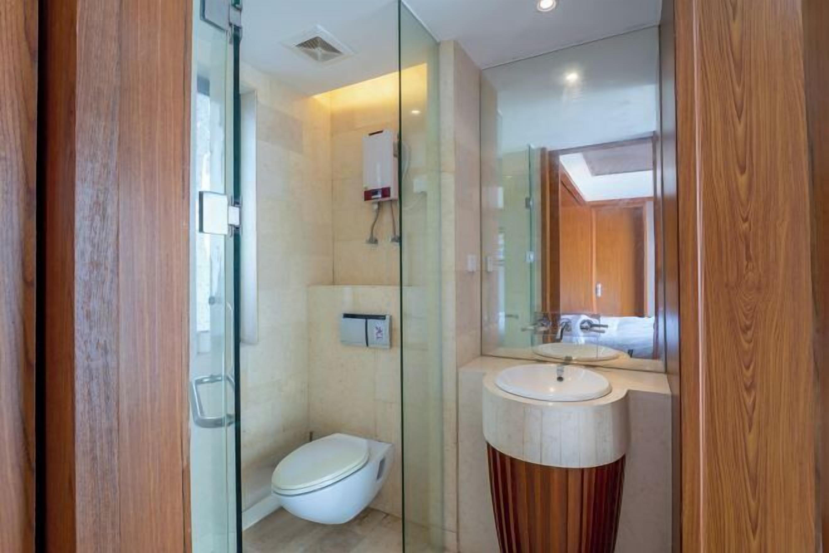 A modern bathroom with a glass shower enclosure, a toilet, and a vanity with a mirror.