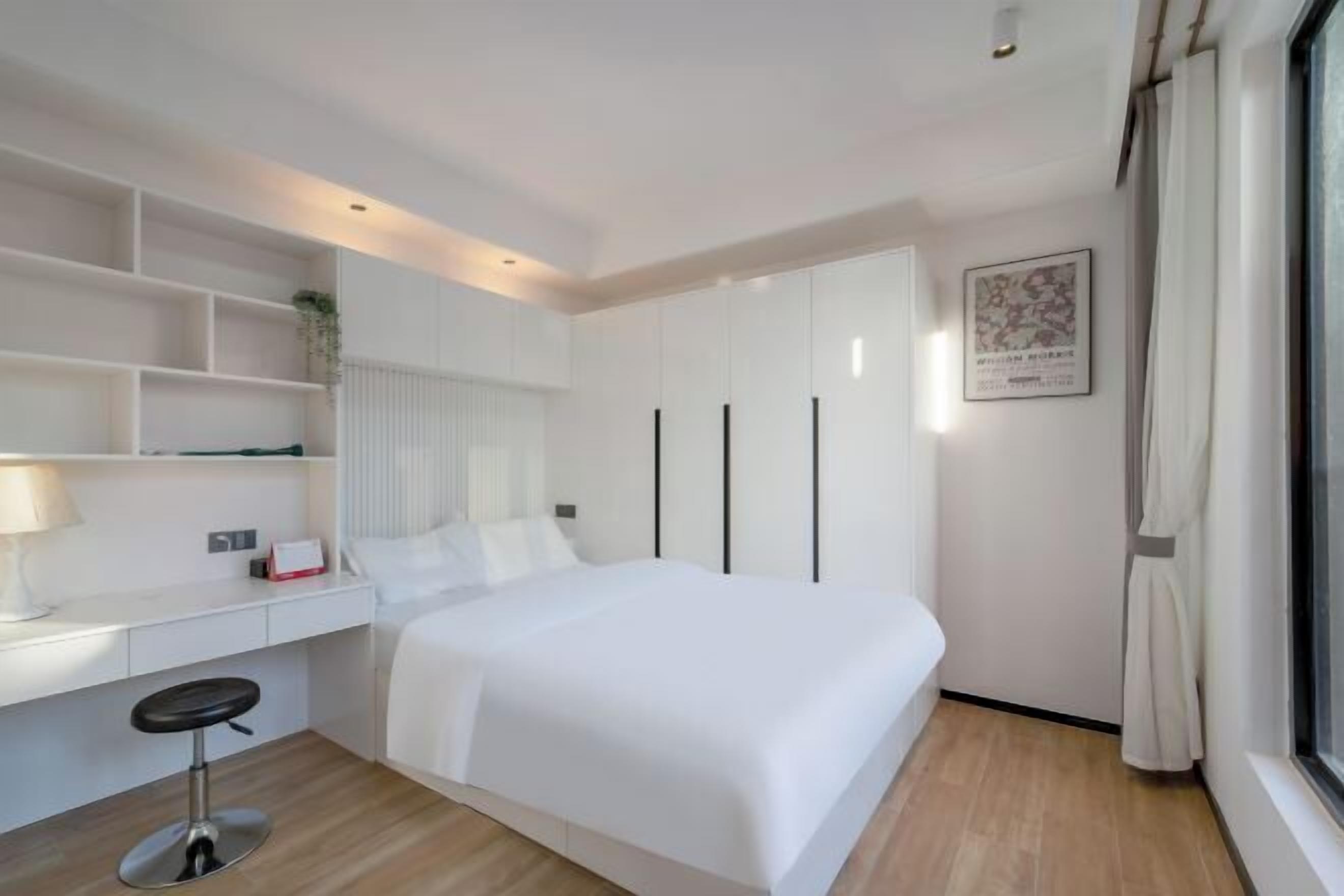 A modern hotel room with a bed, a desk, and a large window.