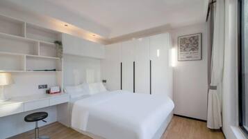 A modern hotel room with a bed, a desk, and a large window.