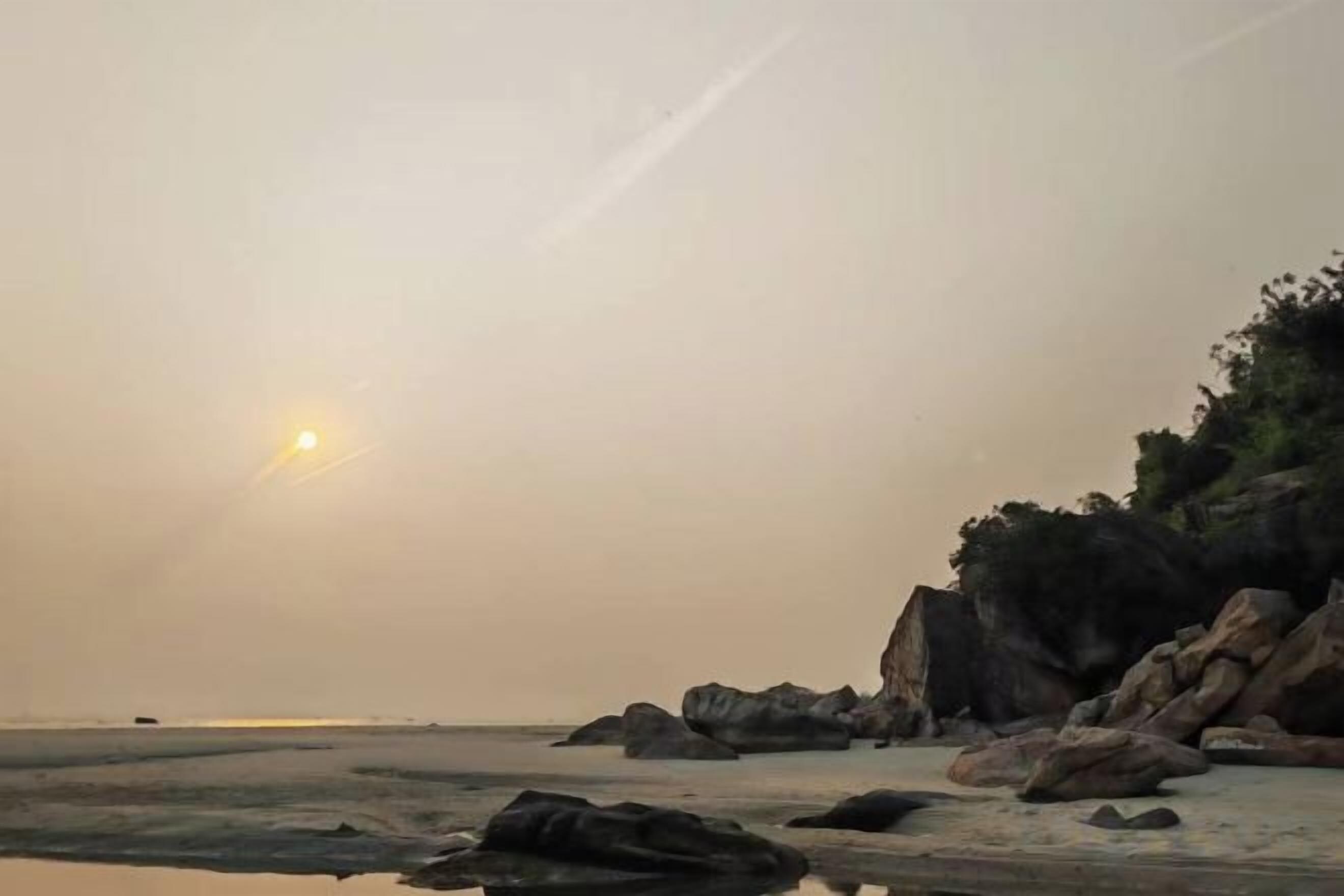 A coastal landscape with rocks and a clear sky.