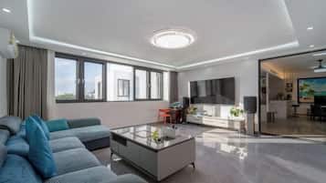 Ein modernes Wohnzimmer mit Sofa, Couchtisch, Fernseher und Küchenzeile.