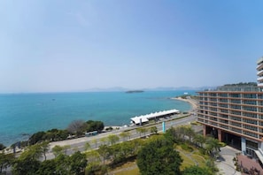 A coastal hotel with a view of the sea, a parking area, and a building with multiple floors. - Xunliao Bay Yijing Holiday Sea-view Hotel (Huidong)