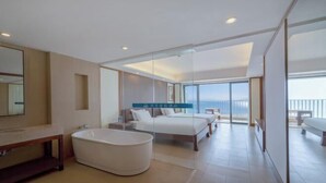 Habitación de hotel moderna con una bañera grande, una cama doble y un balcón con vistas.