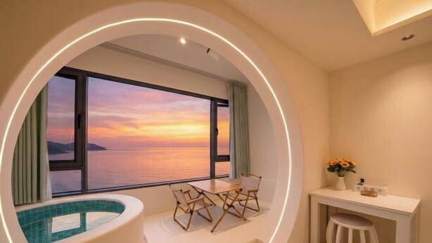 Una habitación con vista al mar al atardecer, una piscina pequeña, una mesa con sillas y un escritorio con taburete.