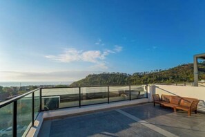 A modern outdoor terrace with a glass railing, a wooden bench, and a view of a hilly landscape. - Xunliao Bay Yijing Holiday Sea-view Hotel (Huidong)