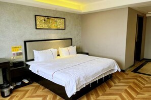 A hotel room with a large bed, a nightstand, a trash bin, and a wall-mounted artwork. - Intercontinental Cangnan Hotel (Cangnan)