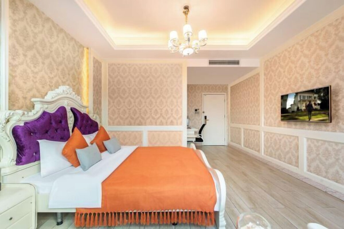 Quarto com uma cama grande, um candelabro e papel de parede estampado.