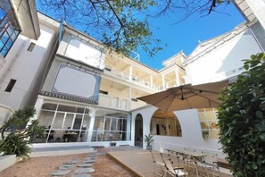 Un patio de varios niveles con asientos al aire libre, un área cubierta y una escalera.