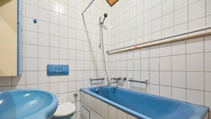 A bathroom with a blue bathtub, a white toilet, and a blue sink.
