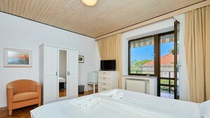A hotel room with a bed, a wardrobe, a television, and a window with a view of a building.
