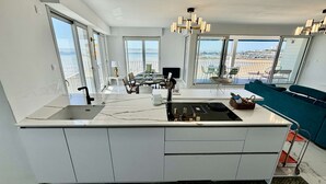 Una cocina moderna con una isla grande, un comedor con vistas y un balcón con vista panorámica de la ciudad.