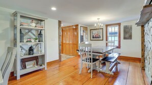 A dining area with a wooden table and chairs, a bookshelf with decorative items, and a view of the outdoors through a window. - Walk to Memorial Park: Pet-Friendly Bethlehem Home (Bethlehem)