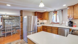A modern kitchen with a stone backsplash, wooden cabinets, stainless steel appliances, and a dining area with a wooden table and chairs. - Walk to Memorial Park: Pet-Friendly Bethlehem Home (Bethlehem)