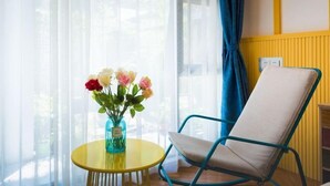 Une pièce avec une table jaune, une chaise bleue et un vase de fleurs.