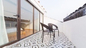 Un balcon doté d’un revêtement de sol à motifs, d’une porte-fenêtre coulissante et de deux chaises.
