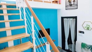 Un escalier avec des marches en bois et des rampes blanches menant à un balcon.
