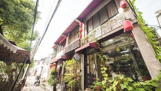 Une rue étroite, bordée de bâtiments des deux côtés, dont certains sont dotés de balcons et de plantes.