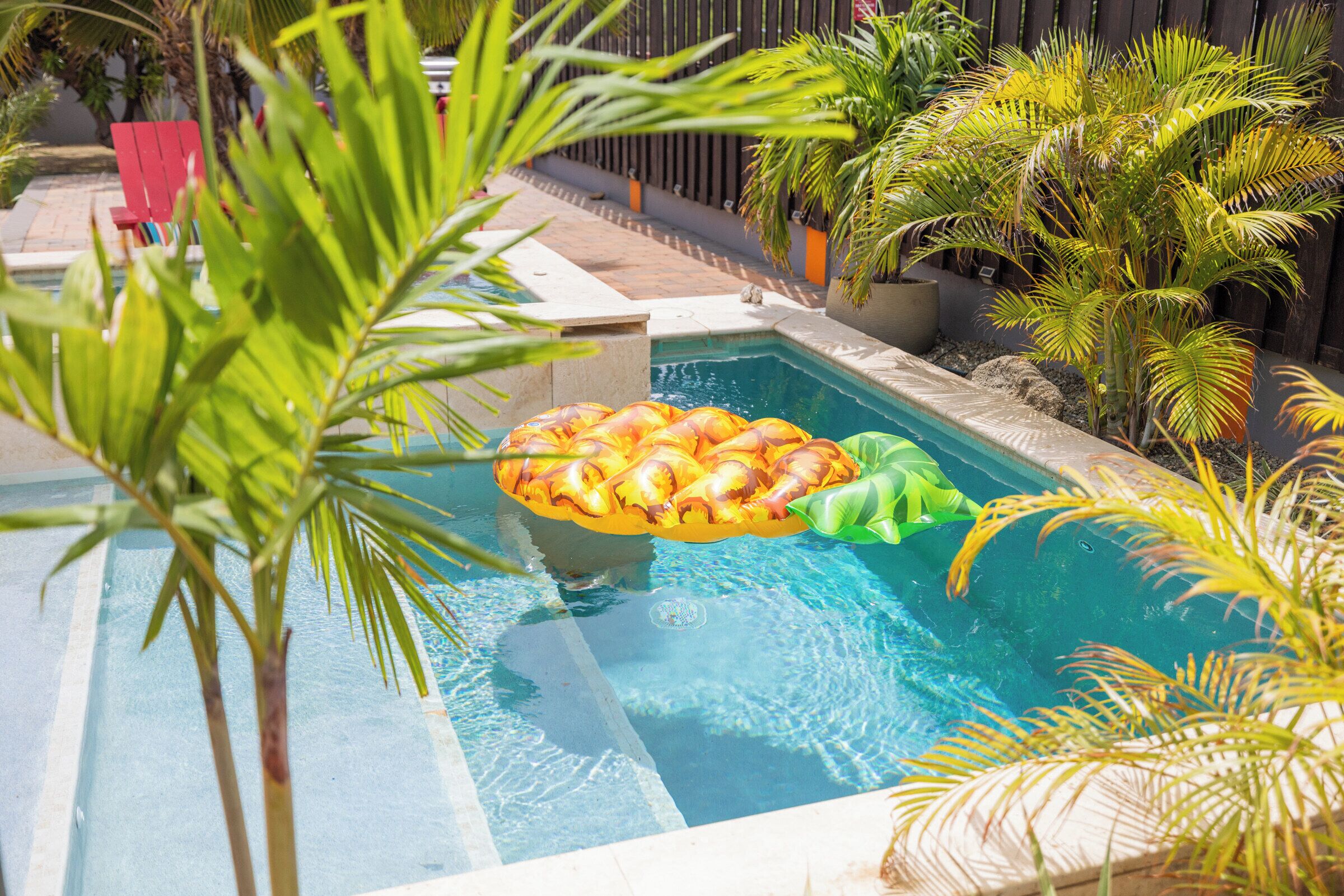 Une piscine avec un matelas gonflable vert et des palmiers tout autour.
