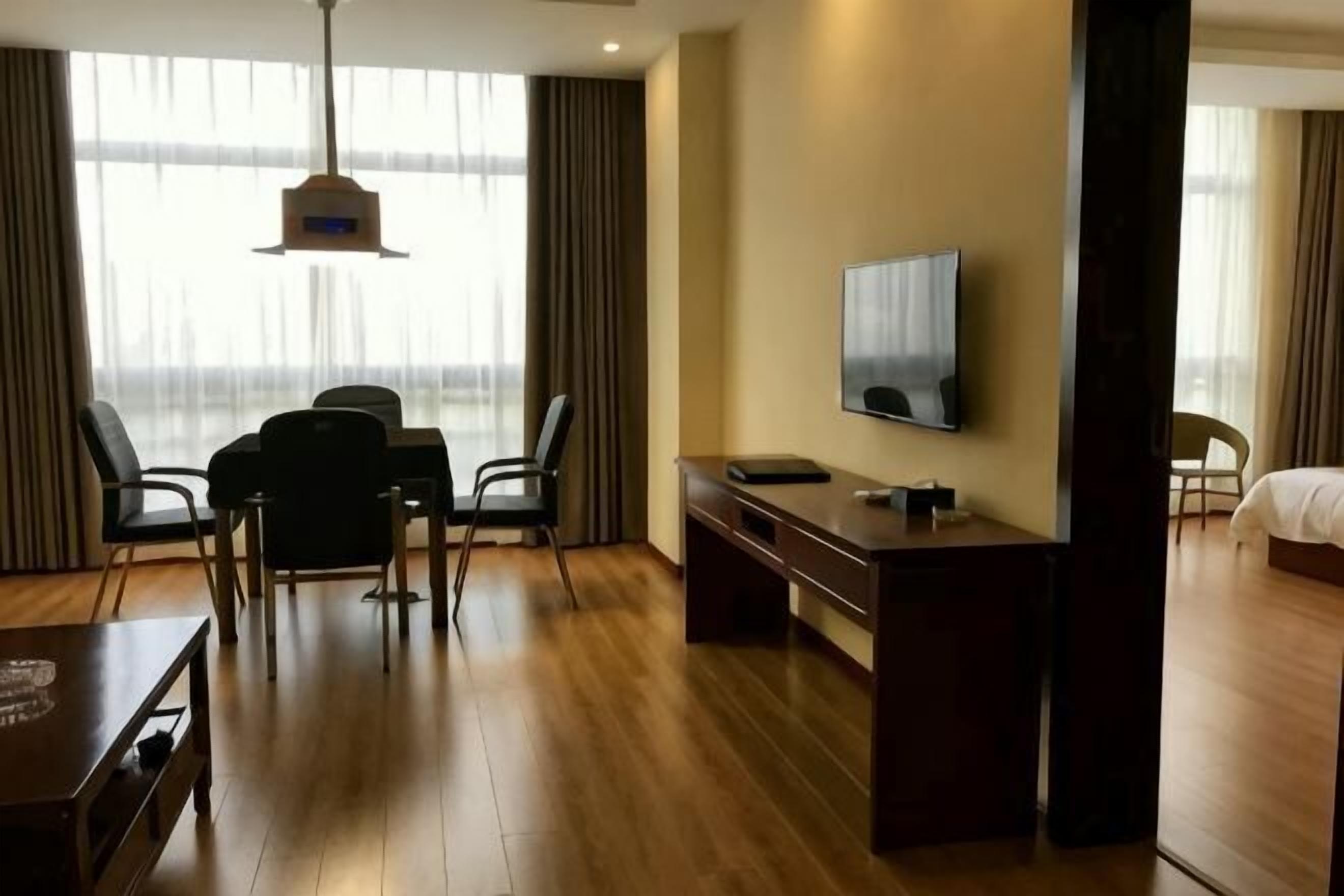 Une chambre d’hôtel avec un plancher en bois, un téléviseur fixé au mur, un bureau et une chaise.