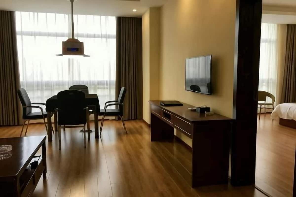 Une chambre d’hôtel avec un plancher en bois, un téléviseur fixé au mur, un bureau et une chaise.