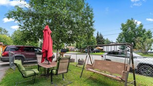 A patio with outdoor furniture, including chairs and a swing set, surrounded by a chain-link fence. - Stylish Studio Suite Near Downtown Anchorage - Explore Alaska's Beauty with Ease (Anchorage)