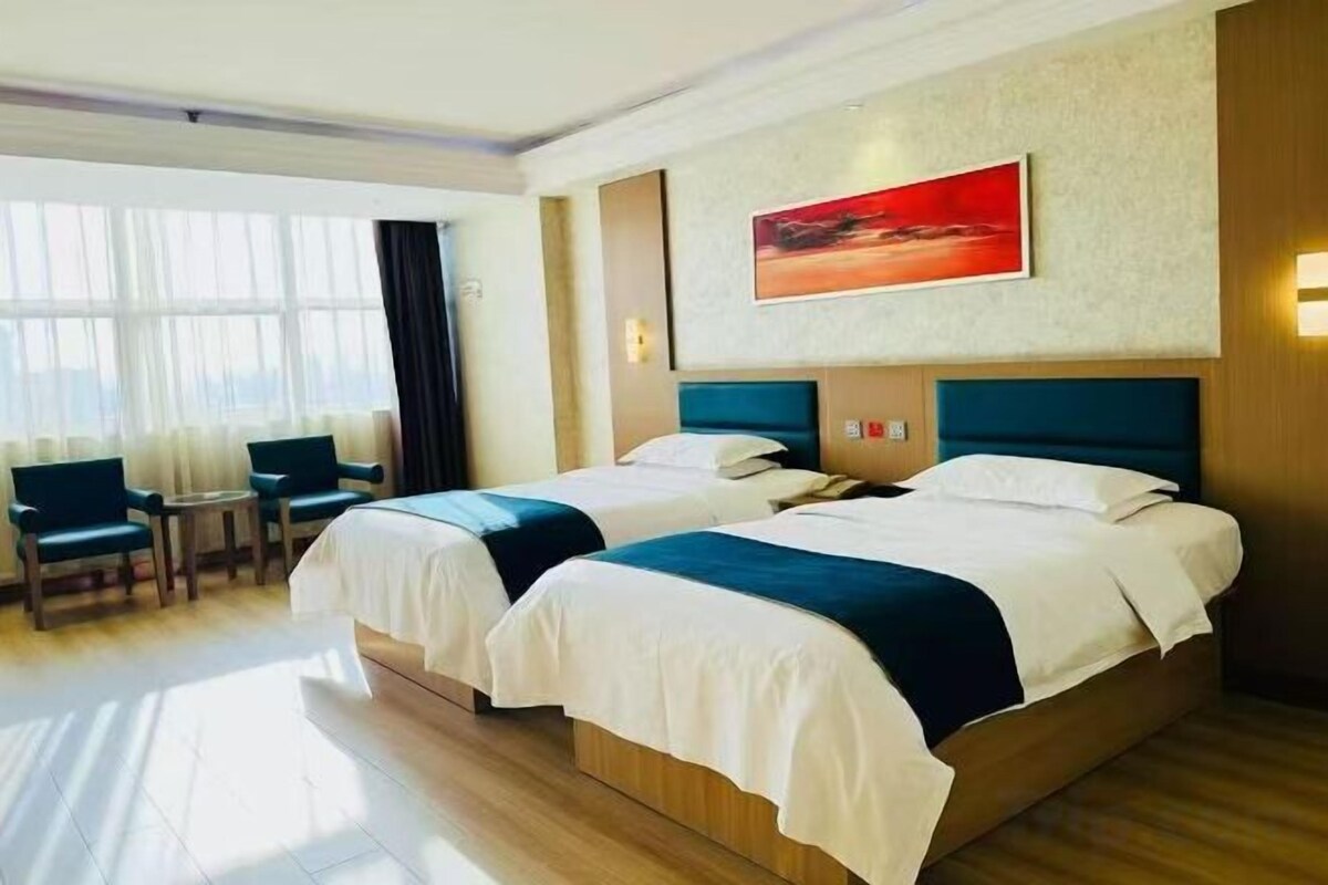 Een hotelkamer met twee bedden, een groot raam en uitzicht op de stad.