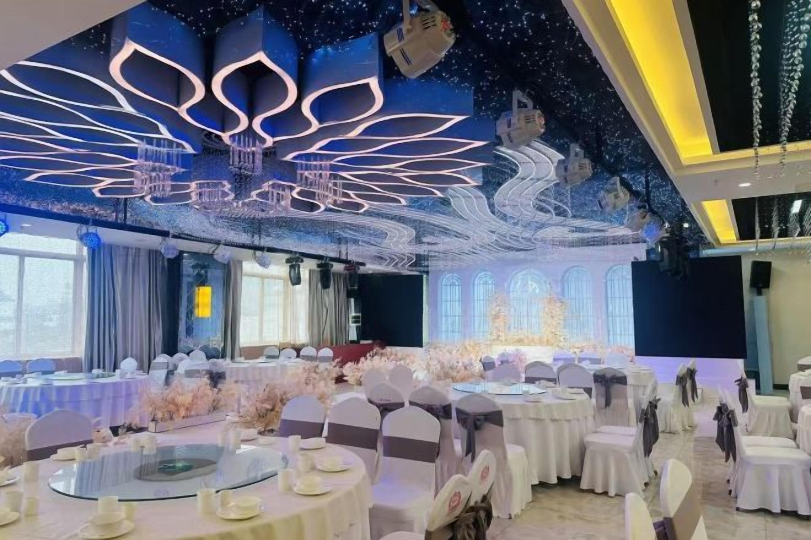 A banquet hall with round tables, white tablecloths, and chairs.