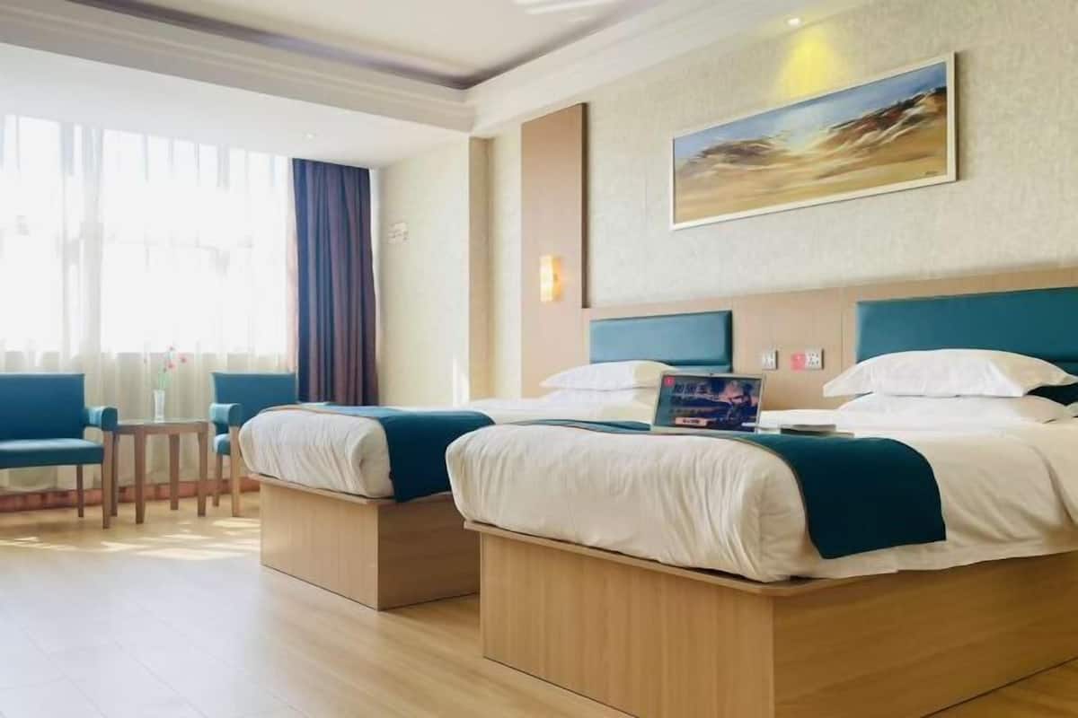 Une chambre d’hôtel avec deux lits, un bureau et une grande fenêtre.