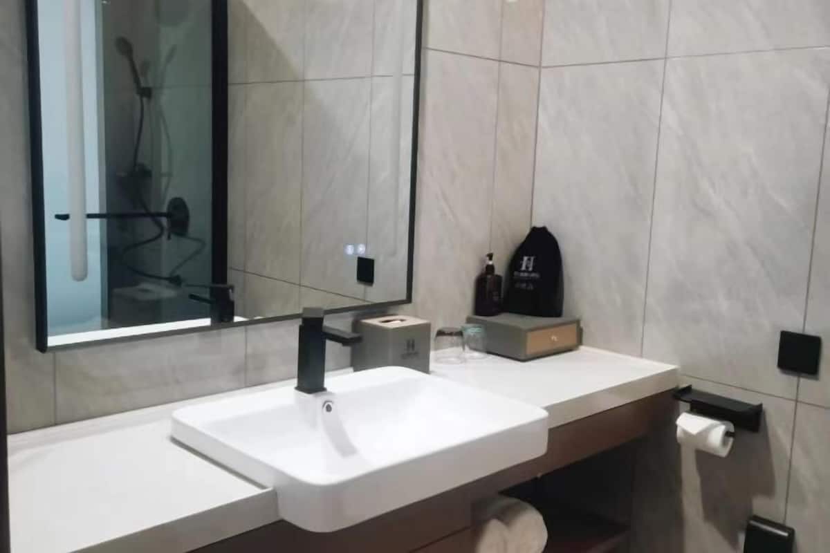 Une salle de bain moderne avec un lavabo blanc, une douche en verre et un miroir.