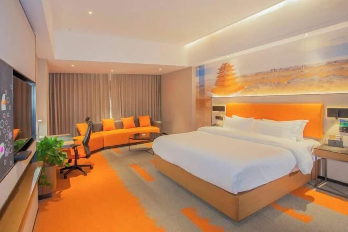 Une chambre d’hôtel moderne, dotée d’un grand lit, d’un canapé, d’un bureau et d’une télévision.