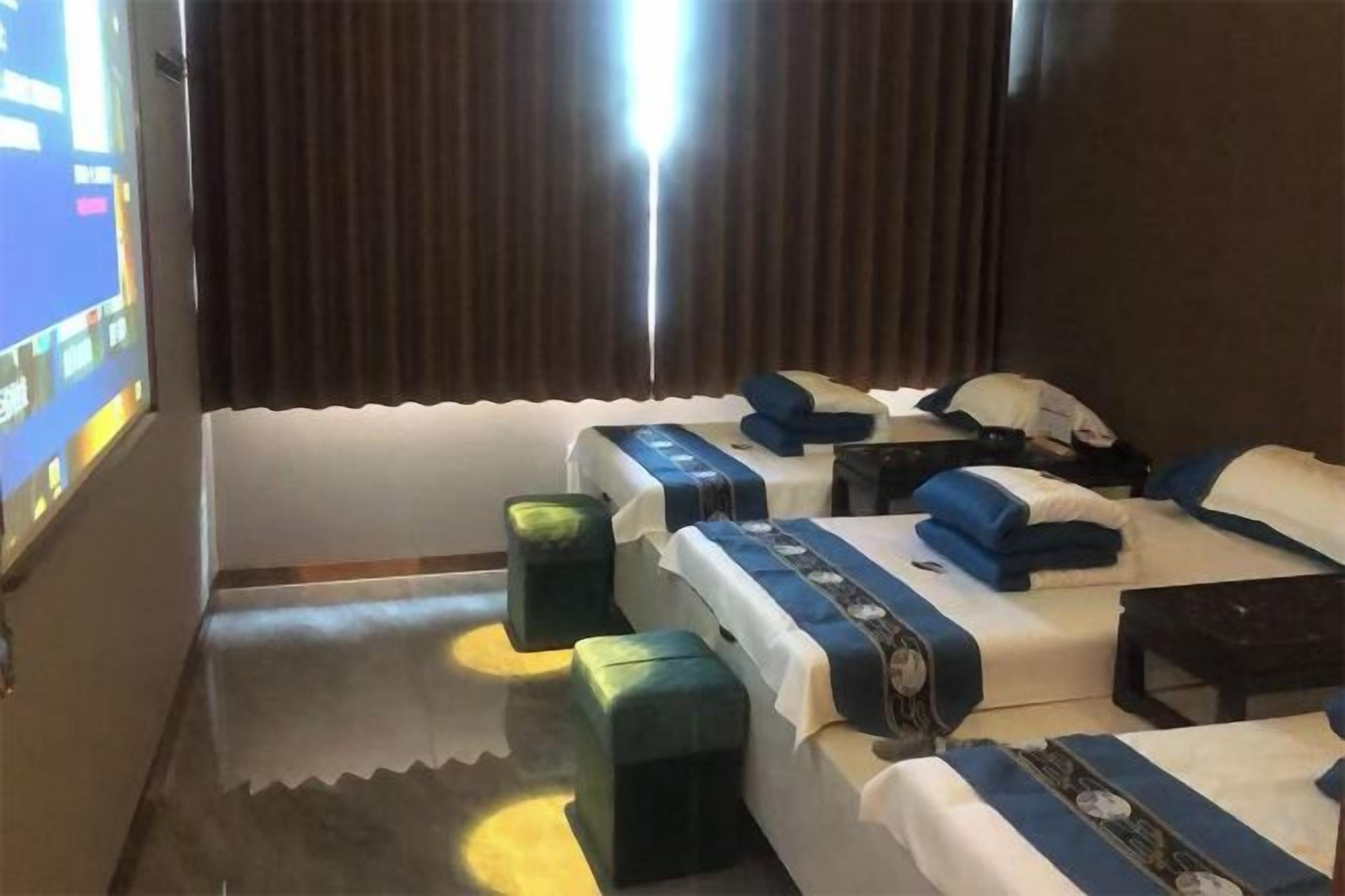 Une chambre d’hôtel avec trois lits, un bureau et une grande fenêtre avec des rideaux.
