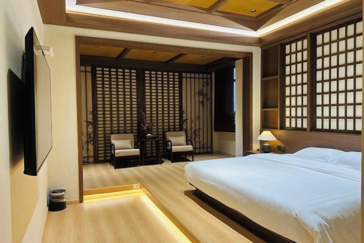 A hotel room with a bed, seating area, and a TV.