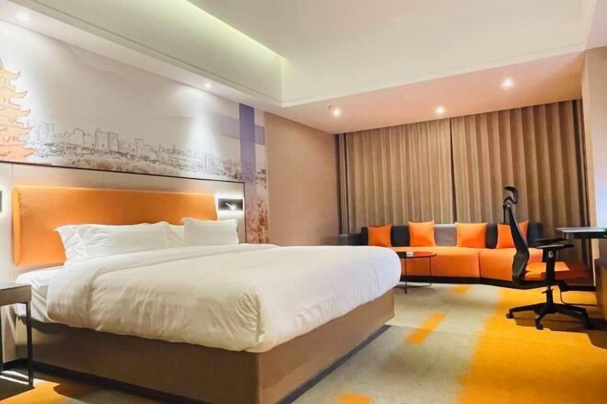 Une chambre d’hôtel avec un grand lit, un canapé, un bureau et une chaise.