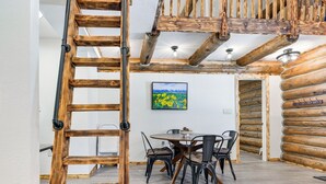 Een eethoek met een houten plafond, een ronde tafel en vier stoelen.