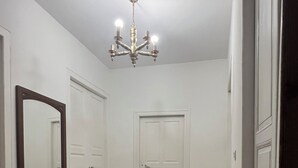A hallway with patterned flooring, a large mirror, and a chandelier.