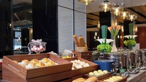 A buffet with various food items, including pastries and bread, arranged on wooden trays. - Hampton by Hilton Xuzhou Huaihai Road (Xuzhou)